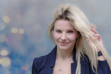 Portrait of happy smiling young cheerful businesswoman standing with flowing hair. Success in business concept studio shot. Blue suit. Multicolor wall background.