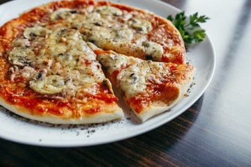 Hot pizza slice with melting cheese on a wooden table.