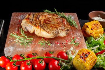 Pieces of roast beef with spices served on black slate.