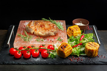 Pieces of roast beef with spices served on black slate.