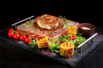 Pieces of roast beef with spices served on black slate.