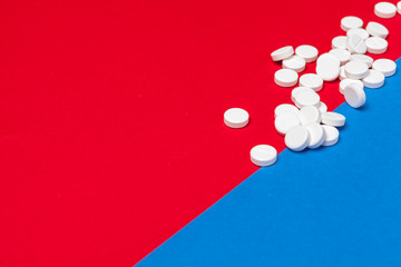 White medical pills on a two color red and blue background