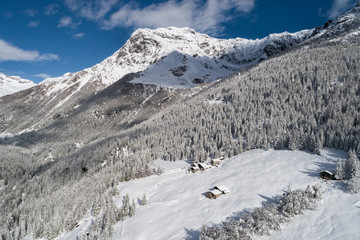 Winter landscape, forest and little village in mountain. Valtellina, Italian Alps