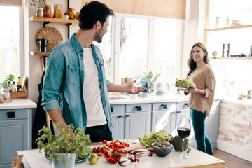 Their own recipe. Beautiful young couple cooking dinner while standing in the kitchen at home
