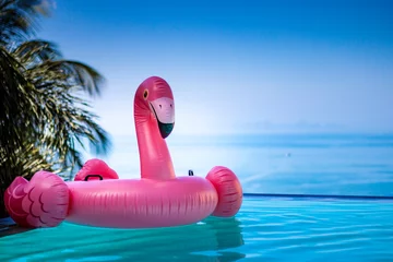 Selbstklebende Fototapeten  Rosa Flamingo im Pool Wasser infinitie aussicht horizont palme © Stankovic