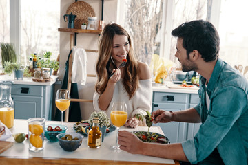Hearts filled with love. Beautiful young couple enjoying healthy breakfast while sitting in the kitchen at home