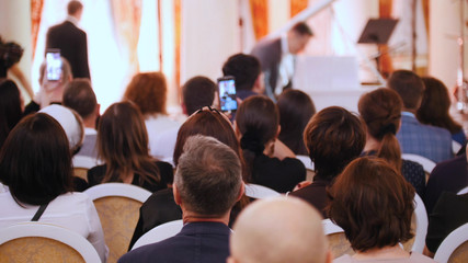 A concert in the concert hall. People sitting in the hall and looking at the artist