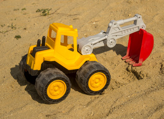 Yellow excavator toy in sand, on the beach. Boy's toys concept - Image