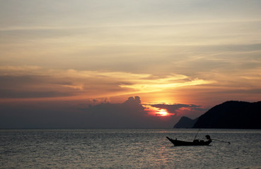 Sunset in Thailand with traditional boat at background