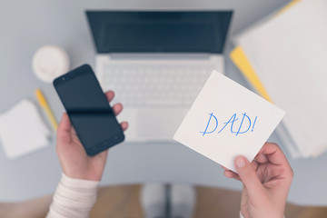 Woman clerk is sitting at office table holding note sticker with reminder dad