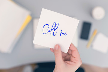 Woman clerk in the office holding paper sticker with the word call me. concept