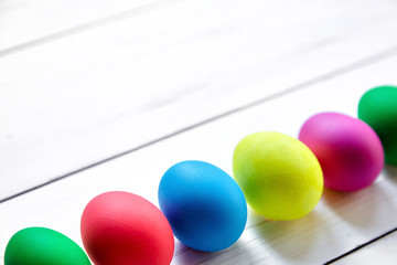 Colorful Easter eggs on white wooden background