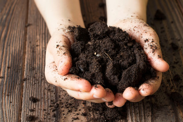 Dark tone color. Close up Child hand carry black and organic soil. Concept earth day.