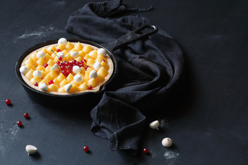 Lemon and White Chocolate Pie decorated with Lemon Curd and Red Currant, served in pan, on black background.