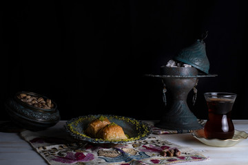 Traditional Arabic/ Turkish dessert baklava with pistachios, and tea, turkish delight dark background with authentic decoration