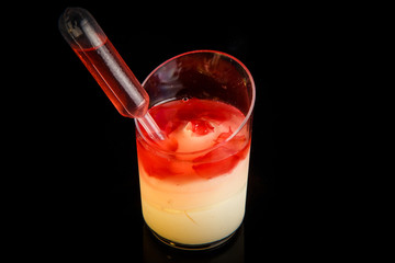 closeup milk mousse dessert with strawberry jam in small plastic glass