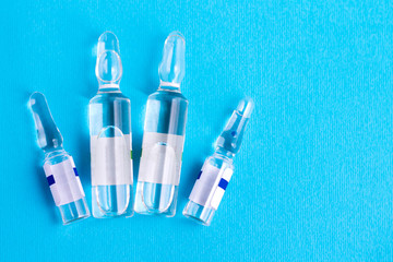 Medical ampoules on a blue background. Vaccine in glass medical ampoules on a blue background. Medical ampoules