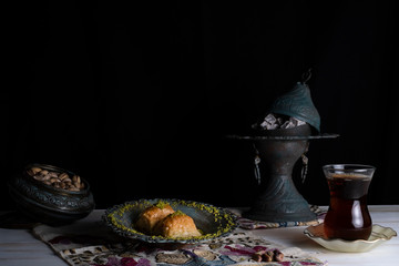 Traditional Arabic/ Turkish dessert baklava with pistachios, and tea, turkish delight dark background with authentic decoration