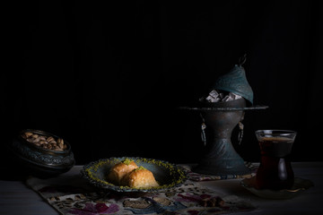 Traditional Arabic/ Turkish dessert baklava with pistachios, and tea, turkish delight dark background with authentic decoration