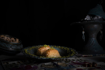 Traditional Arabic/ Turkish dessert baklava with pistachios, and tea, turkish delight dark background with authentic decoration