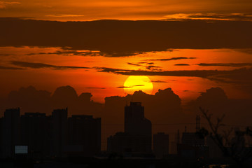 Fototapeta premium The sunset, golden sky and clouds behind the tall buildings In a busy city