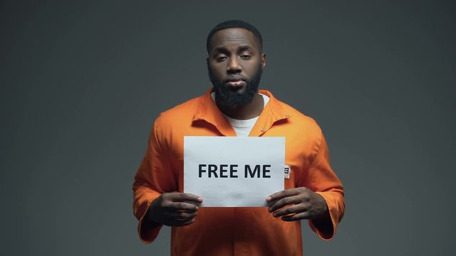 African-american prisoner holding Free me sign in cell, innocent asking for help