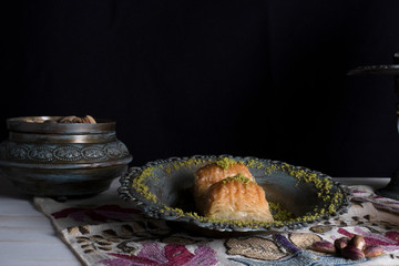Traditional Arabic/ Turkish dessert baklava with pistachios, and tea, turkish delight dark background with authentic decoration