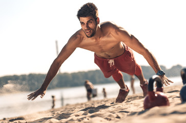 Young man doing fitness workout at a beach on a sunny day.