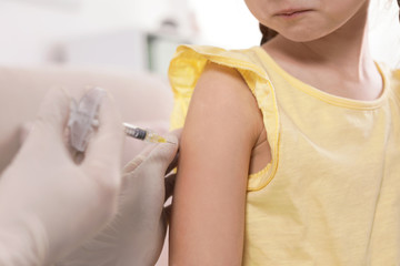 Family doctor vaccinating little child at home, closeup