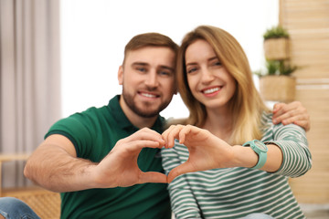 Happy couple making heart with their hands indoors