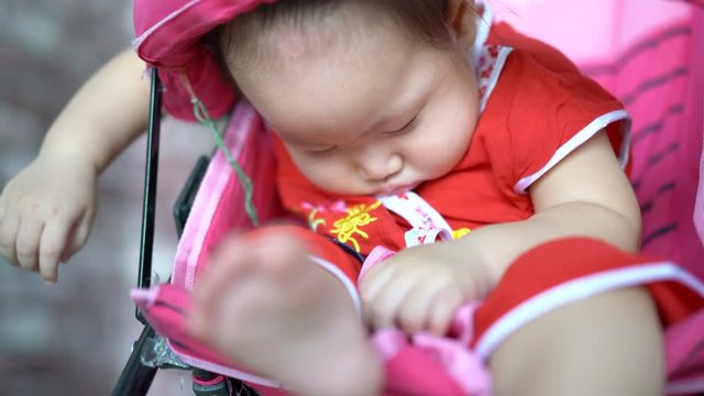Asian baby girl sleeping in stroller. Handheld shot, 4K