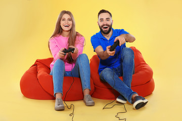 Emotional couple playing video games with controllers on color background © New Africa