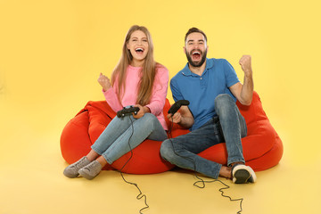 Emotional couple playing video games with controllers on color background © New Africa