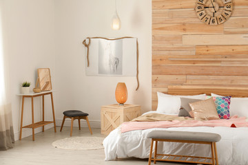 Stylish room interior with comfortable bed near wooden wall