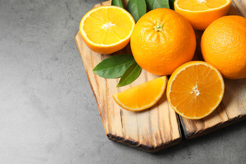 Wooden board with ripe oranges on grey background. Space for text