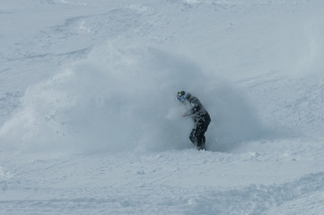 A snowboarder making a powder turn on a piste covered with fresh snow. Avoriaz, France