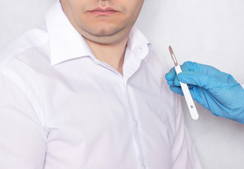 A doctor holds a scalpel on the background of a patient with a double chin, plastic surgery and plastic