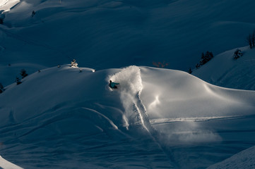 A snowboarder making a powder turn on a piste covered with fresh snow on a sunny morning. Avoriaz,...