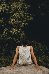 boy sitting relaxing in nature, man next to many trees, young man observing the trees