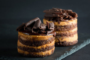 Chocolate cakes on black slatter board with mint, coffee beans on dark background, closeup photo. Fresh, tasty dessert food concept. 