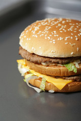 Close-up of delicious fresh burger with lettuce, cheese and onion on a dark background