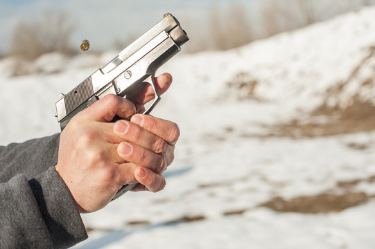 Close-up detail view of shooter hands holding gun and shooting