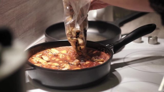 Adding more mussles in a tomato sause and stirring it