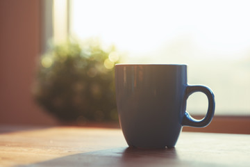 coffee cup on wooden table in morning sunlight, copy space
