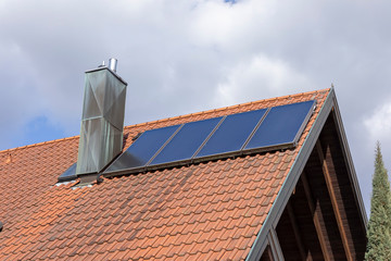 Fototapeta na wymiar Solarzelle und Schornstein auf einem Dach