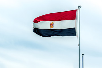 the flag of Egypt develops against the white sky. Horizontal frame