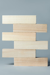 a pyramid of wooden cubes lying on top of each other with space for an inscription, on an uneven white background. Vertical frame