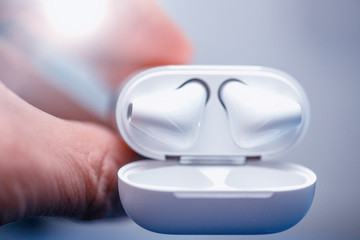 Modern wireless earphones held by man's hand