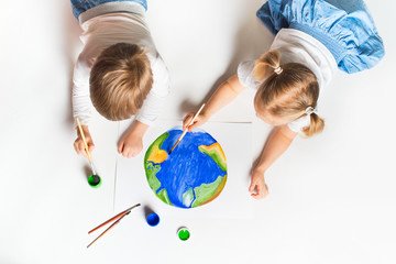 Ecology concept with two prety little kids painting earth on white background