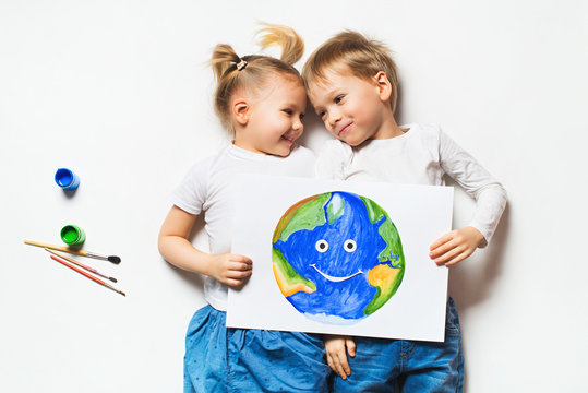 Ecology concept with two prety little kids painting earth on white background